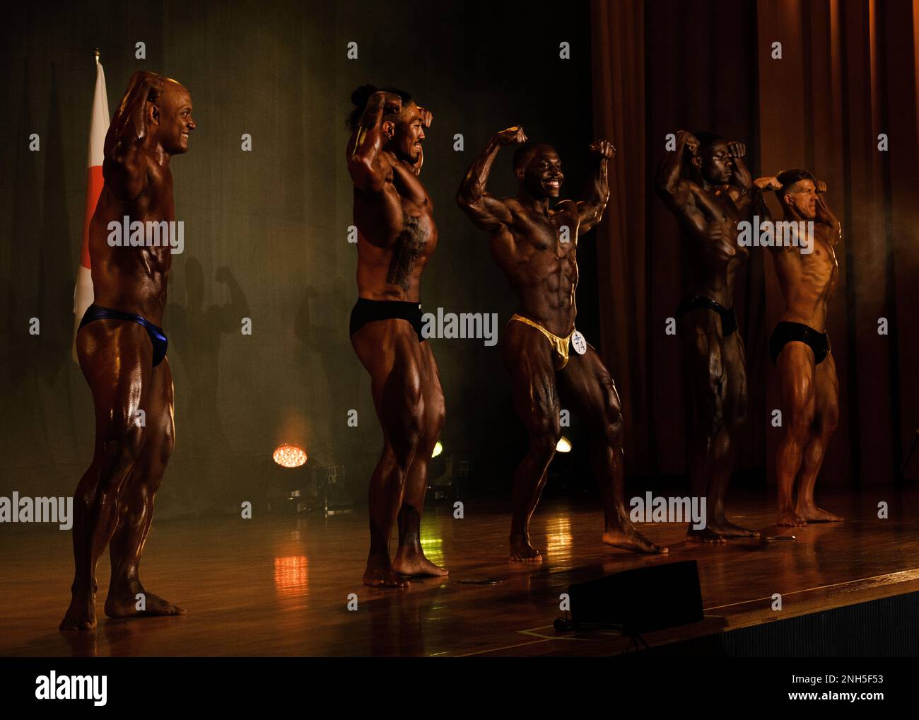 I concorrenti si esibiscono in una posa in prima-doppia-bicipa all'Estremo Oriente Bodybuilding Competition 2022, a Camp Forster, Giappone, il 17 luglio 2022. Dopo le singole procedure, i concorrenti eseguono delle pose obbligatorie affinché i giudici possano confrontarle. Foto Stock