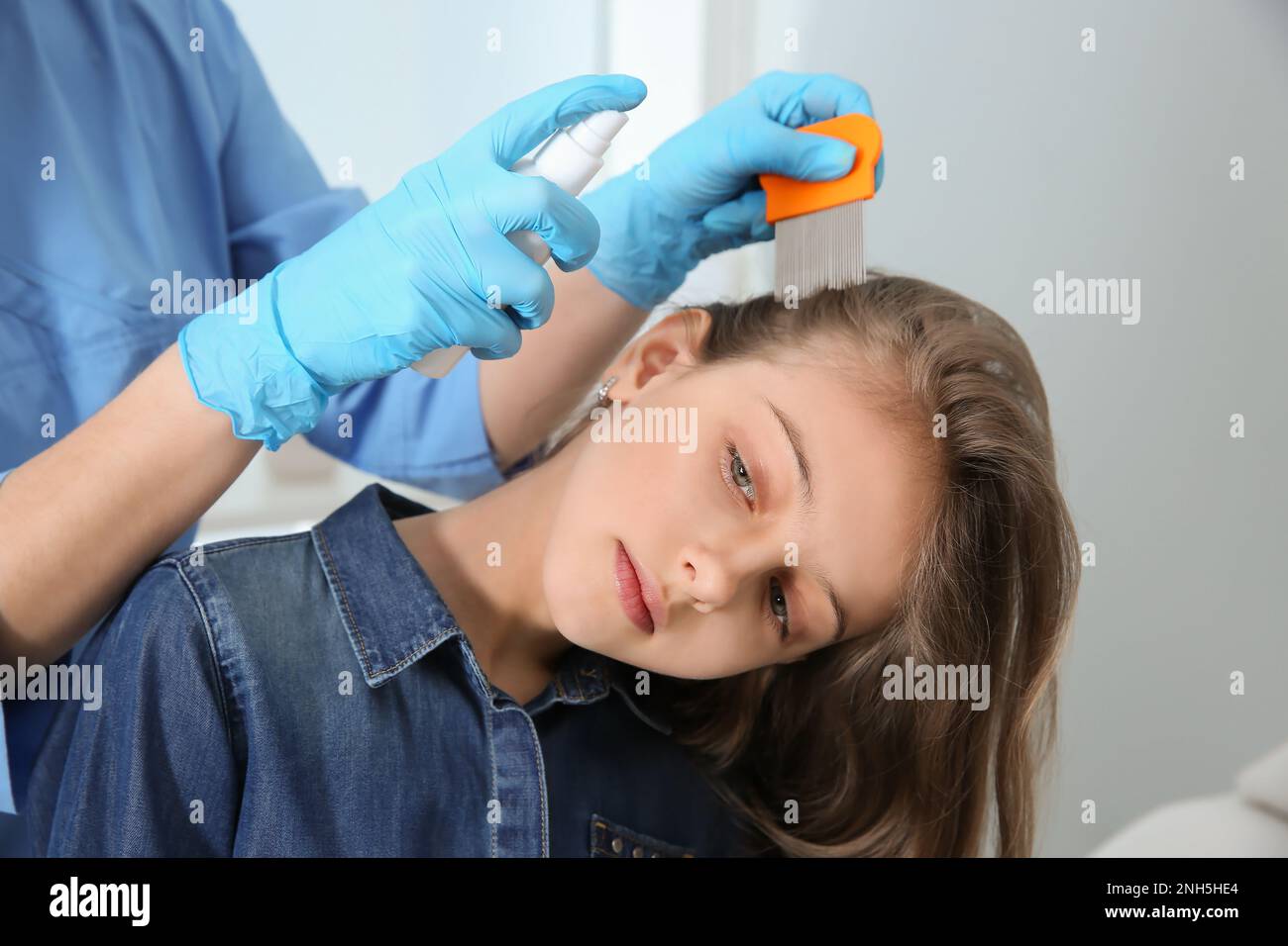 Medico che usa nit pettine e spray sui capelli della ragazza all'interno. Trattamento antighiaccio Foto Stock