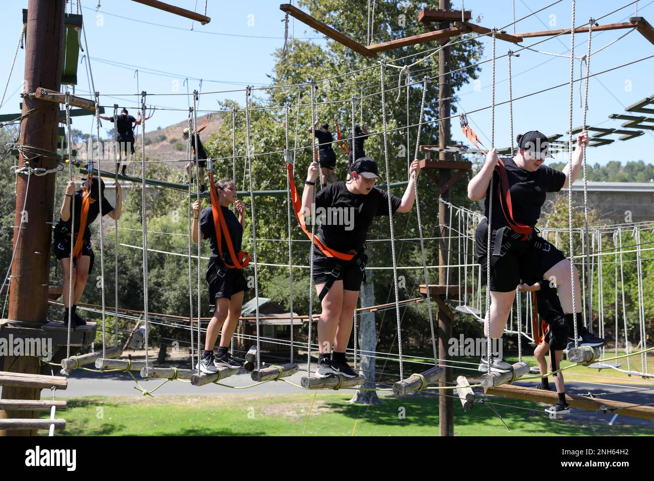 I candidati della Sunburst Youth Challenge Academy, Joint Forces Training base, California, si seguono attraverso un ostacolo di corda al corso Orange County Ropes di Anaheim, California, 19 luglio 2022. I volontari di Sunburst sono indicati come candidati per le prime due settimane, mettendoli attraverso varie sfide mentali e fisiche prima di guadagnare il titolo di Cadet. Foto Stock