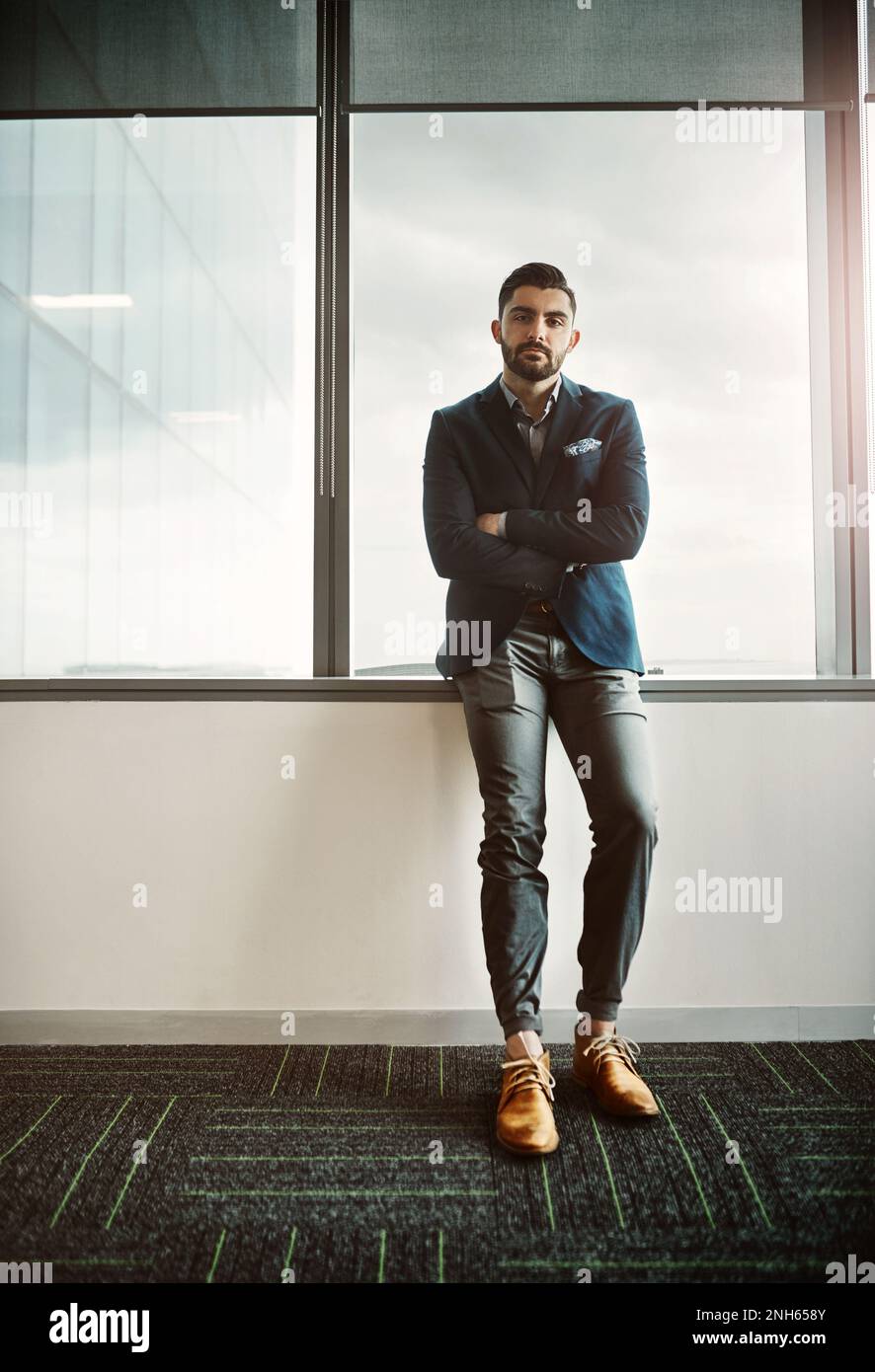 Conosca il valore nel conoscere il vostro valore. Ritratto di un giovane uomo d'affari sicuro che lavora in un ufficio moderno. Foto Stock