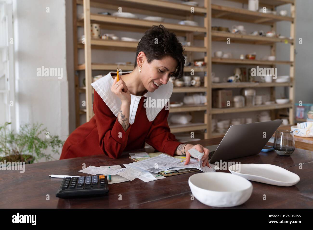 Soddisfatto riuscito femmina studio proprietario di ceramica calcolare il reddito, facendo contabilità Foto Stock