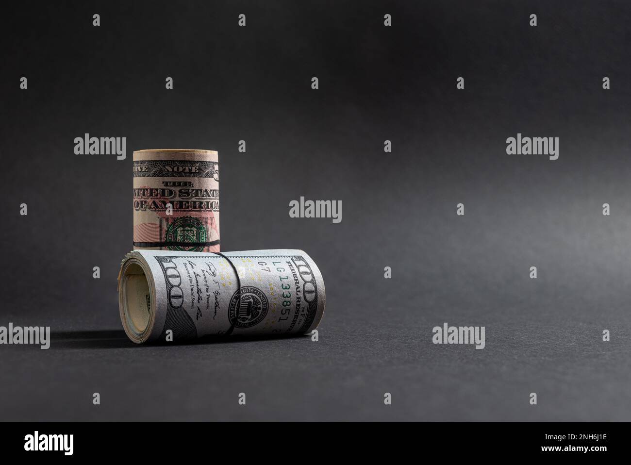 Rotoli di 50 e 100 dollari USA in piedi su sfondo scuro Foto Stock