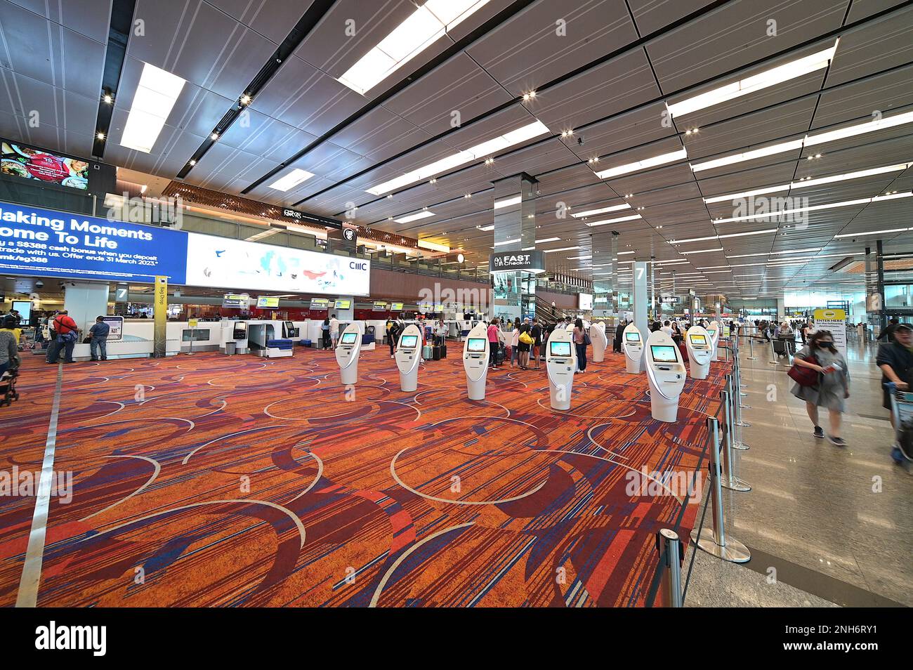 Banchi self-service presso la sala partenze del Terminal 1, Aeroporto Changi di Singapore, con chioschi di consegna bagagli sulla sinistra, febbraio 2023 Foto Stock