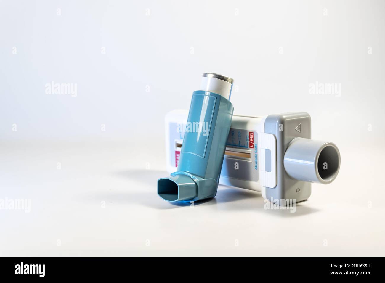 Dispositivi medici per malattie polmonari come asma, allergia e BPCO, misuratore di flusso di picco e spray blu pompa inalatore su sfondo grigio chiaro, spazio copia, s Foto Stock