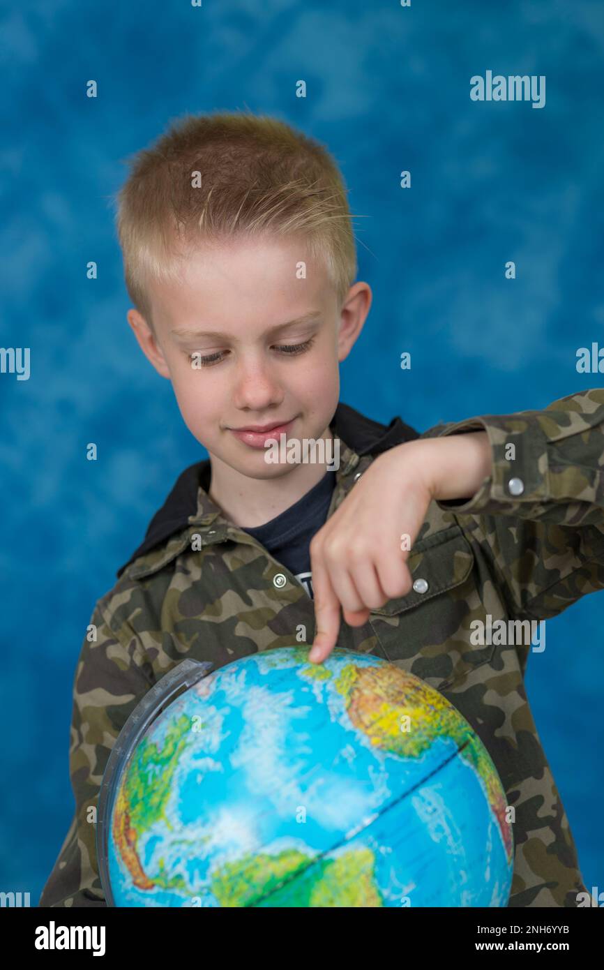 Piccolo ragazzo che mostra un globo terrestre contemporaneo della Terra Foto Stock