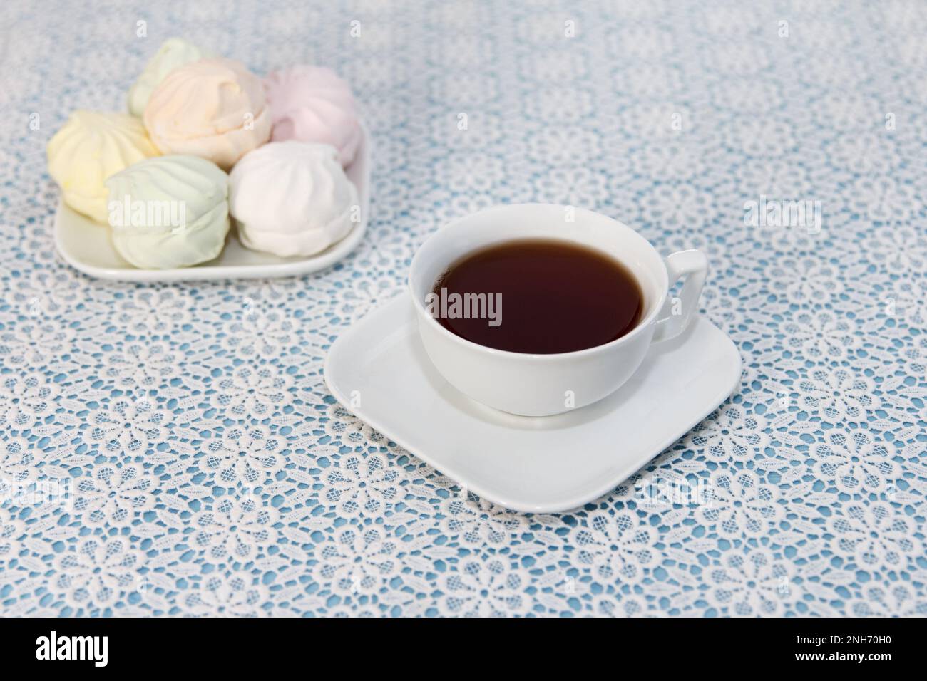 Tradizionale delizioso tè preparato in una tazza e marshmallows aria si trovano sul tavolo, un dolce dessert. Ora del tè. Foto Stock