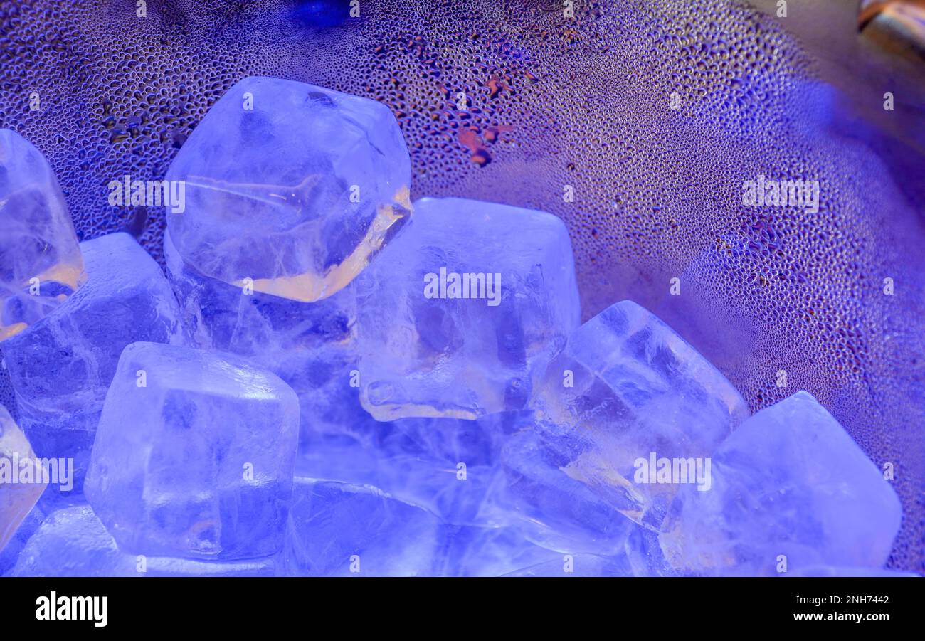 Cubetti di ghiaccio e piccole bolle, illuminati da luci viola e blu Foto Stock