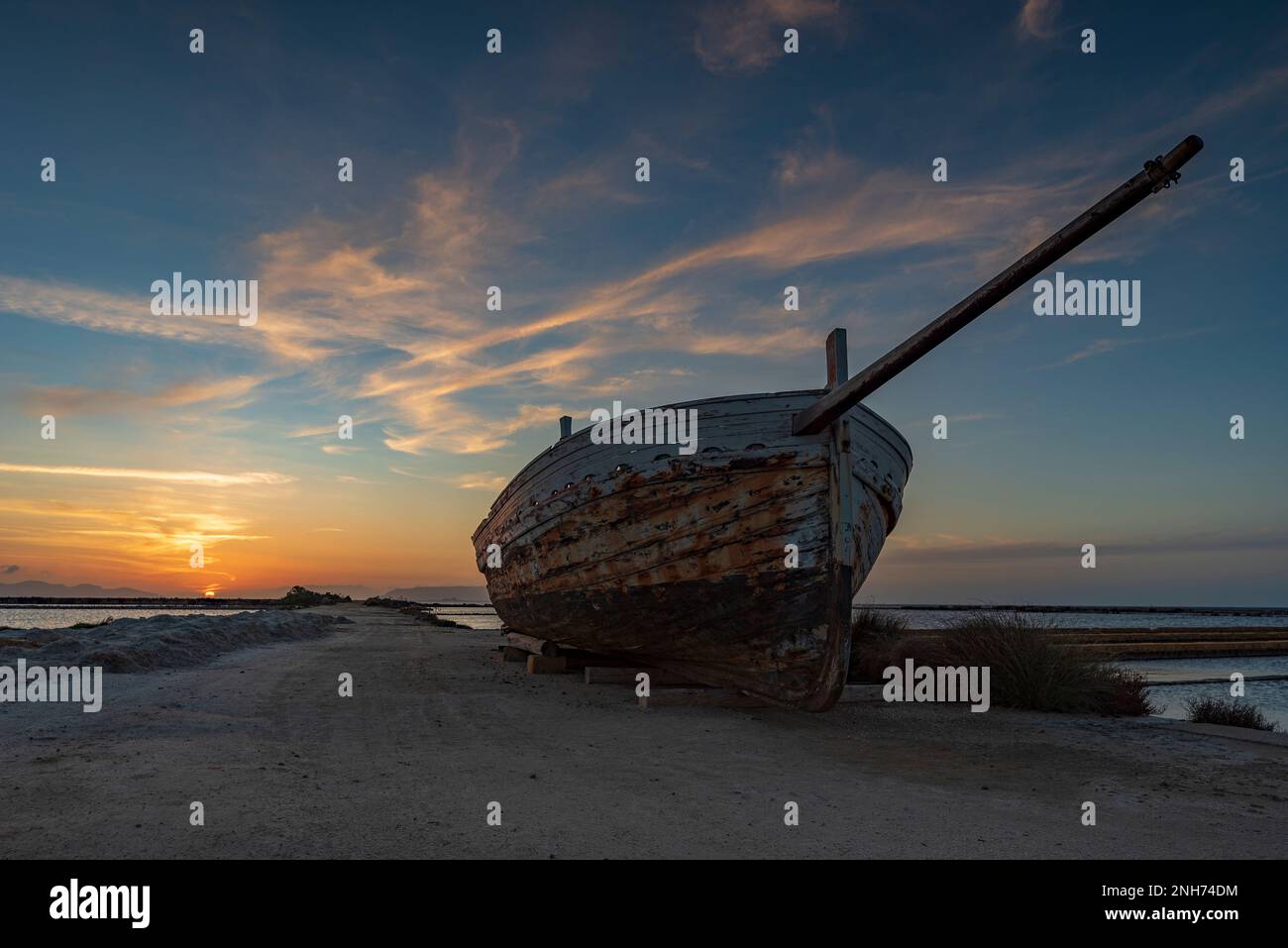 Tramonto su una vecchia barca da pesca, saline di Trapani Foto Stock