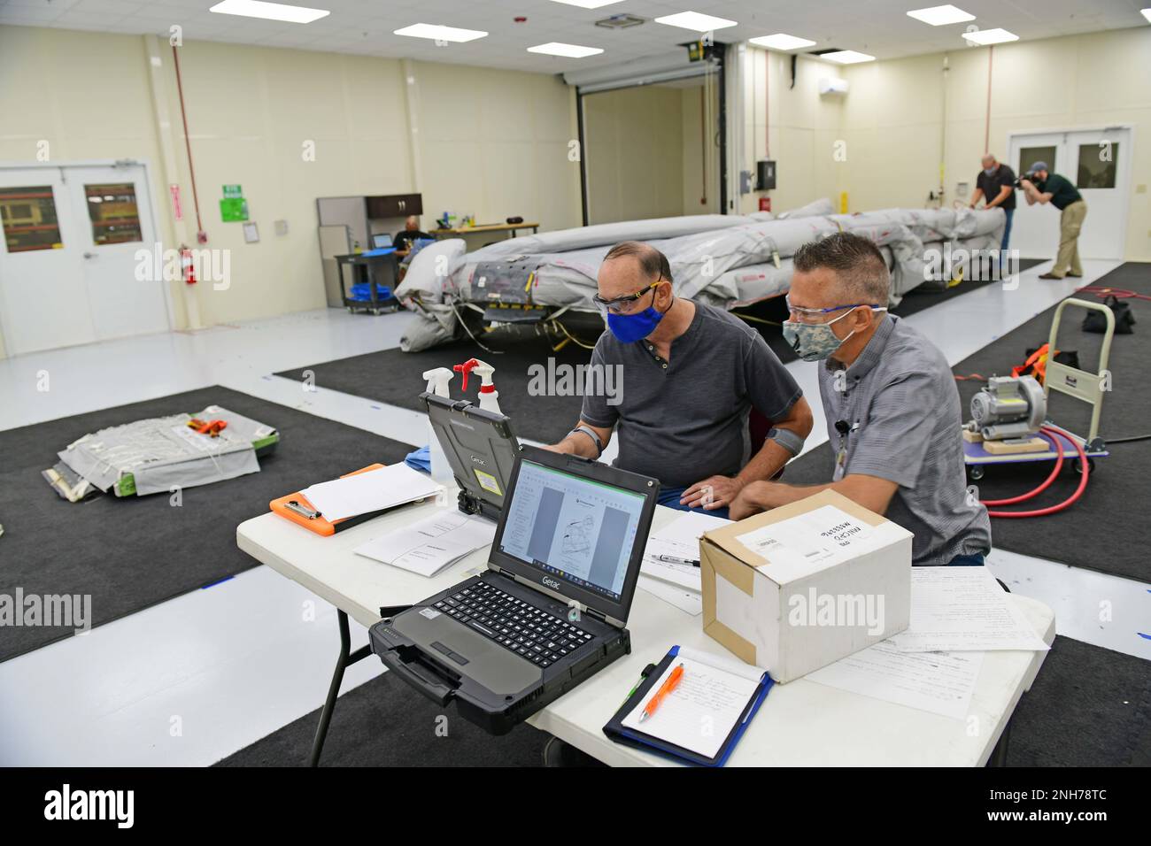 Matthew Miller, Right, 572nd Commodities Maintenance Support Squadron Life Support Survival Equipment Repairer, e Mark Runshaw, 572nd CMXS Life Support Survival Equipment Repairer, rivedere le norme prima di ispezionare un carrello/zattera per portaerei KC-46 presso la Robins Air Force base, Georgia, 20 luglio 2022. I riparatori delle attrezzature di sopravvivenza hanno gonfiato e ispezionato lo scivolo/zattera della portiera durante la formazione di routine. Foto Stock