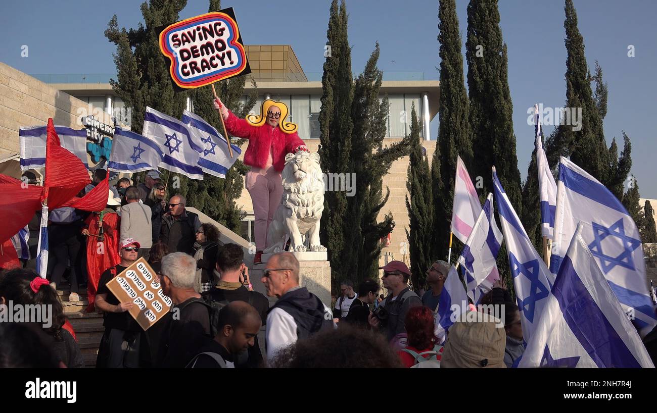 GERUSALEMME, ISRAELE - 20 FEBBRAIO: Un manifestante anti-governativo in costume ha un segno che recita: "Salvare la democrazia!” E altri detengono bandiere israeliane durante una manifestazione di massa al di fuori del parlamento israeliano (Knesset) contro il primo turno di votazioni sul nuovo piano del sistema giudiziario del governo israeliano il 20 febbraio 2023, a Gerusalemme, Israele. Credit: Eddie Gerald/Alamy Live News Foto Stock