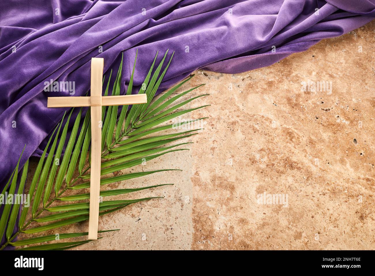 Tempo di Quaresima, settimana Santa e venerdì Santo. Palm lasciare e croce su sfondo di pietra Foto Stock