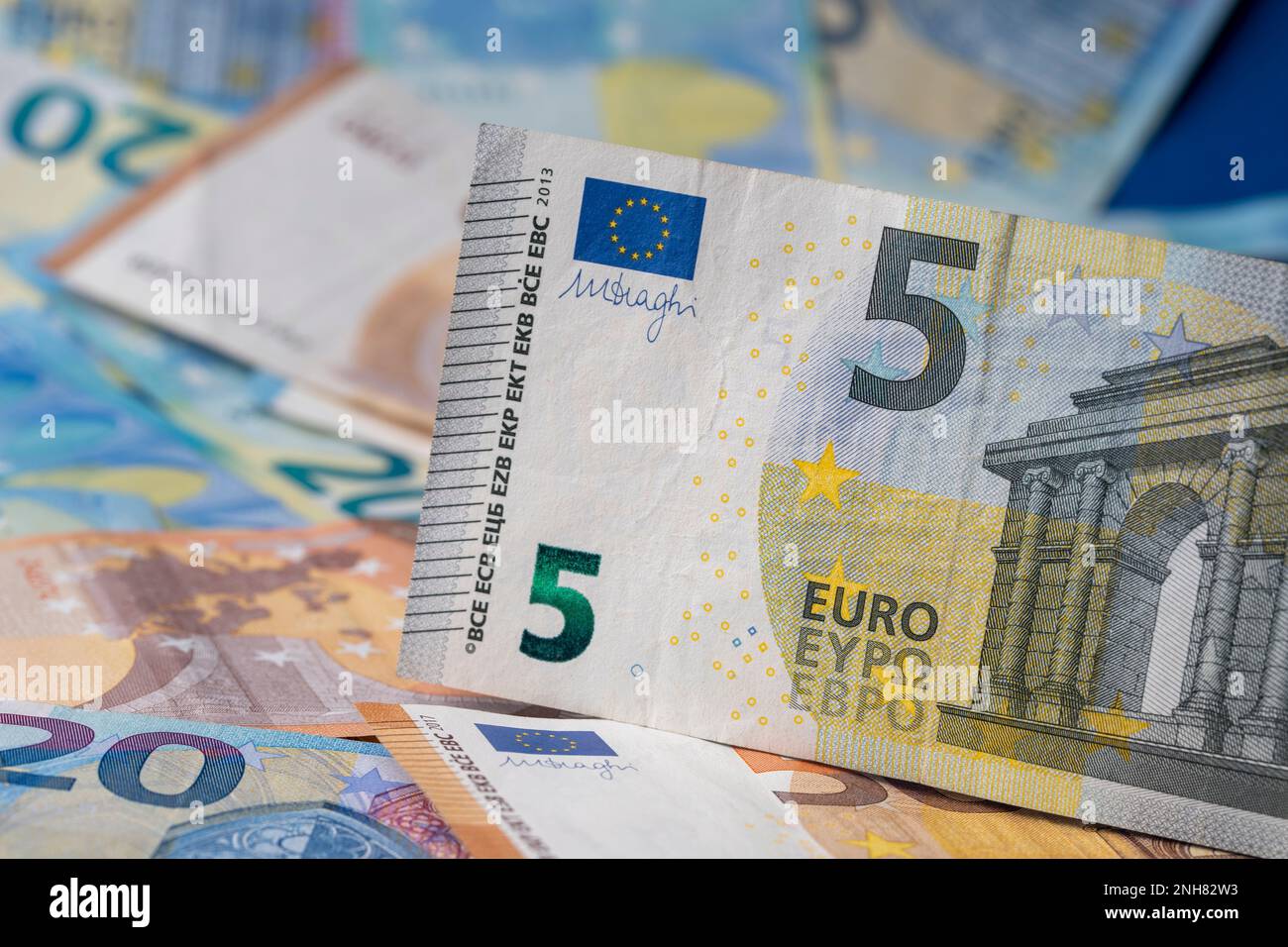 Una pila di banconote sul tavolo. Cinque euro di carta moneta in primo piano. Banconote miste in euro in background. Foto Stock