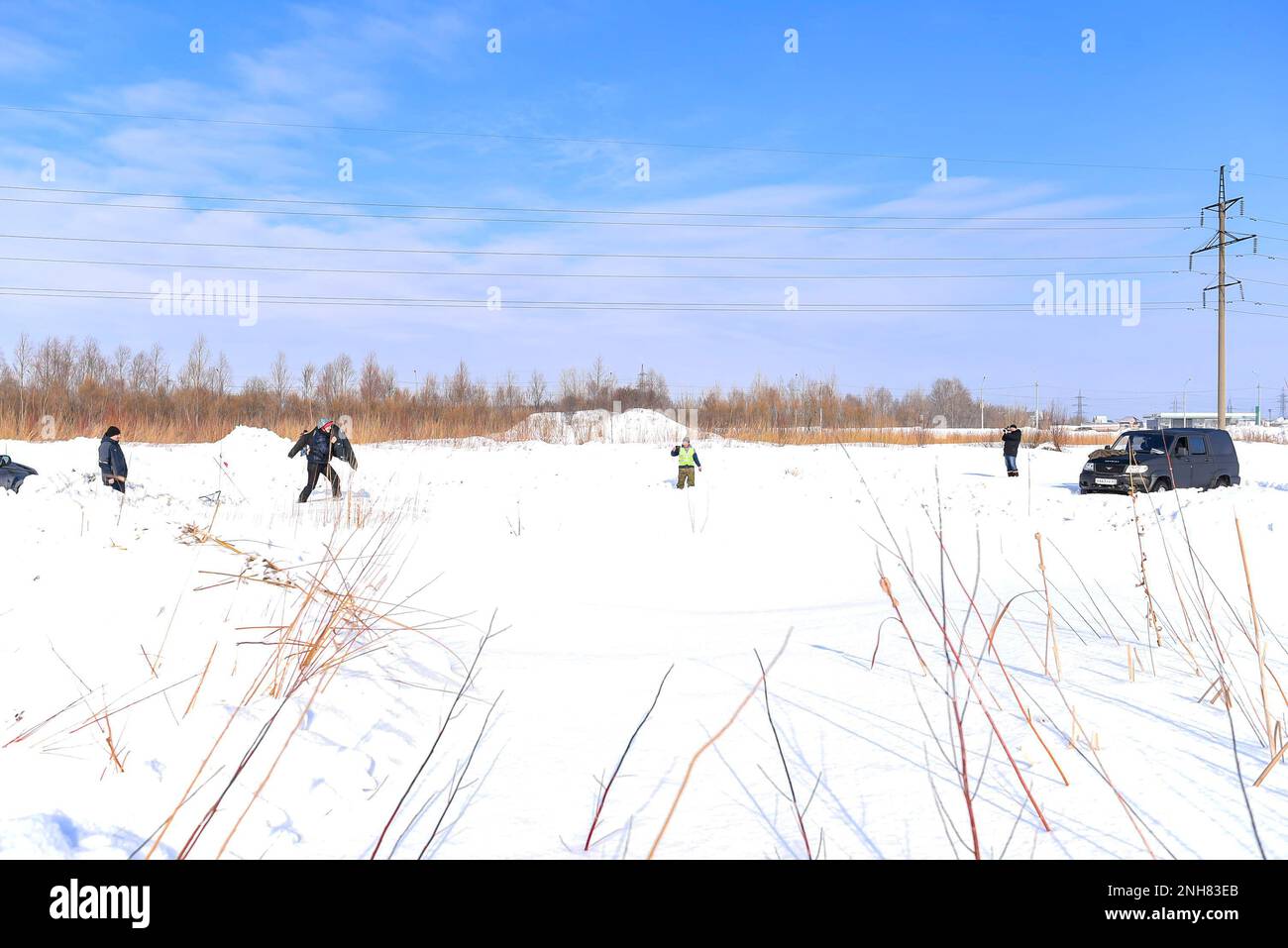 Il SUV russo offroad "UAZ Patriot 4x4" in inverno nella neve si trova accanto a persone che giocano a giochi di guerra. Foto Stock