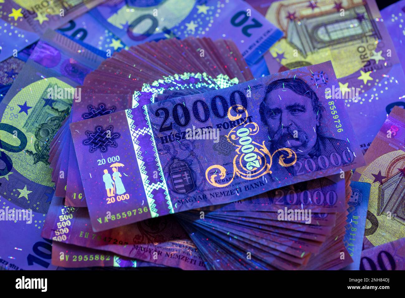 Per verificare l'autenticità del denaro. 20.000 banconote HUF in luce UV, banconote in euro sullo sfondo. L'immagine potrebbe contenere rumore e grana. Foto Stock