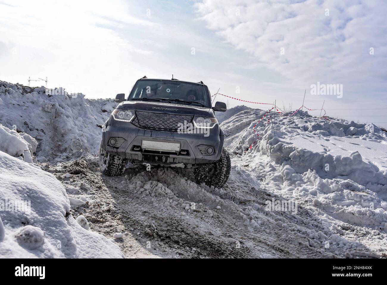 Il SUV russo 'UAZ Patriot' va rapidamente su una strada innevata nel campo in inverno, aggrappandosi alla ruota paracolpi. Foto Stock