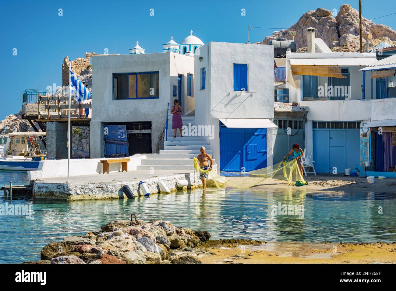 Gente che fissa reti da pesca nel caratteristico villaggio di Firopotamos, Milos Foto Stock