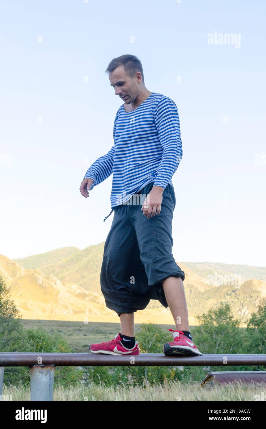 Uomo con i pantaloni larghi per yoga e sneakers 'Nike' sale nella palestra  nella giungla nella Repubblica Altai Foto stock - Alamy