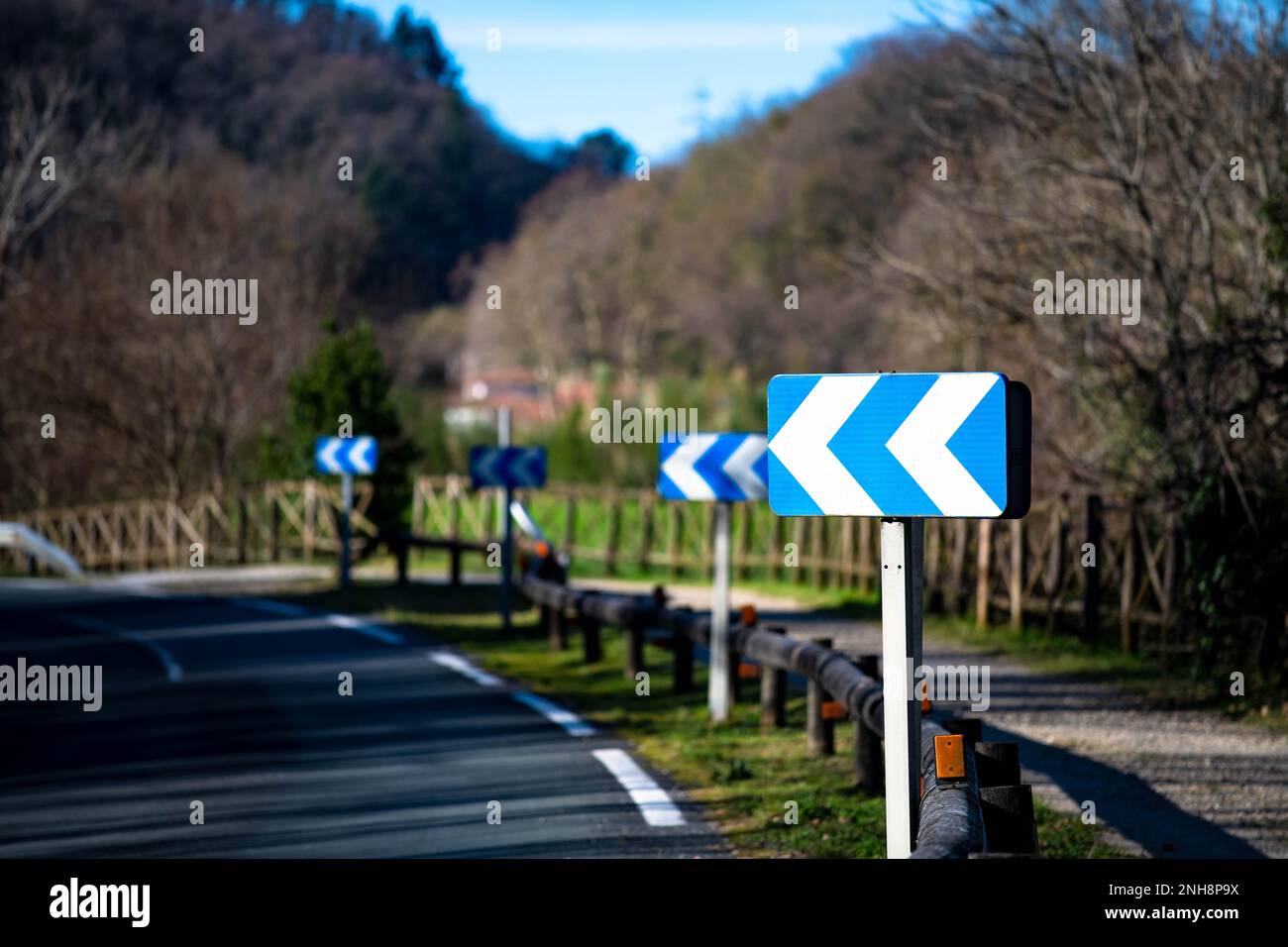 Cartello stradale striato blu brillante "curva strada a sinistra" Foto Stock