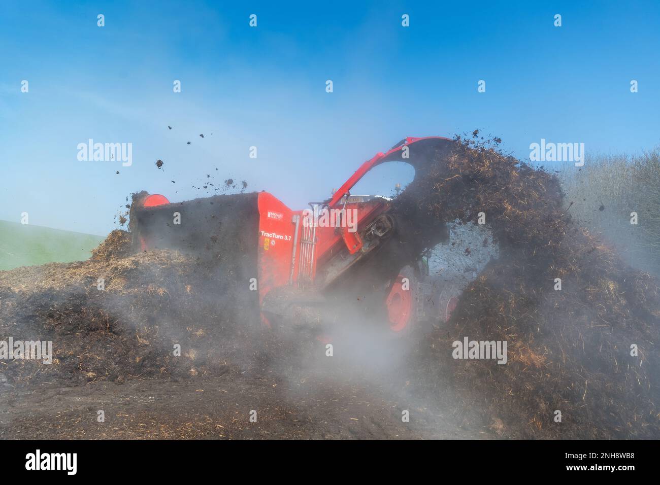 Girando un mucchio di concime sopra fare composto per spargere su terreno agricolo, che aiuta ad aumentare la qualità del suolo. North Yorkshire, Regno Unito. Foto Stock