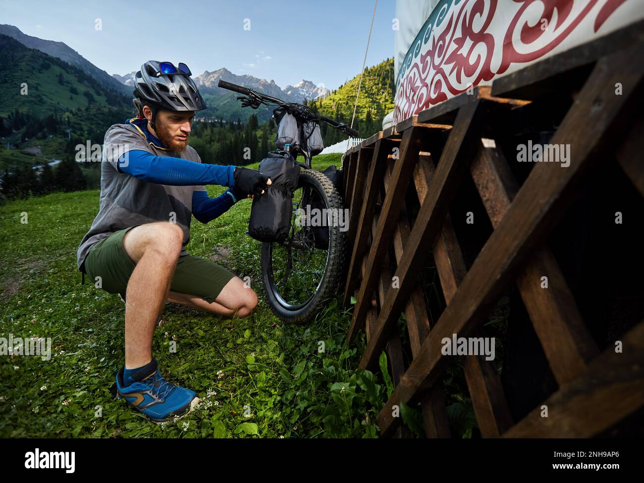 Uomo con greggi e chiudere la sua borsa turistica in mountain bike vicino a casa Nomad Yurt ad Almaty, Kazakistan. Bicicletta Extreme Sport e bicicletta fuori Foto Stock