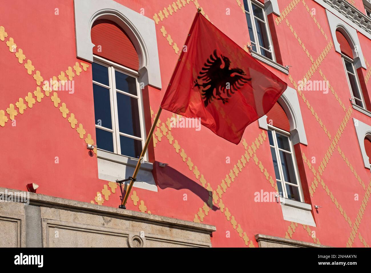 Bandiera rossa dell'Albania con l'aquila nera a doppia testa dalla silhouette sulla facciata a Tirana, capitale dell'Albania Foto Stock