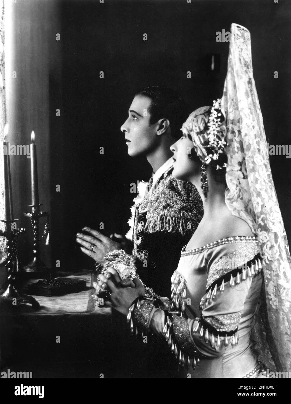 1922 , USA : l'attore del film muto RUDOLPH VALENTINO ( Rodolfo Guglielmi , 1895 - 1926 ) con LILA LEE , Still publicitary for BLOOD AND SAND ( Sangue e arena ) di Fred Niblo , dal romano di Blasco Ibanez ( 1908 ) - CINEMA MUTO - RODOLFO - atto cinematografico - LATINO LOVER - italoamericano - italo americano - italo-americano - emigrante - emigrante - italo-americano - ritratto - ritratto - torero - toreador - profilo - mantiglia - pizzo - pizzo - preghiera - preghiera - pregare - ingrassare - Brillantina - candele ---- Archivio GBB Foto Stock
