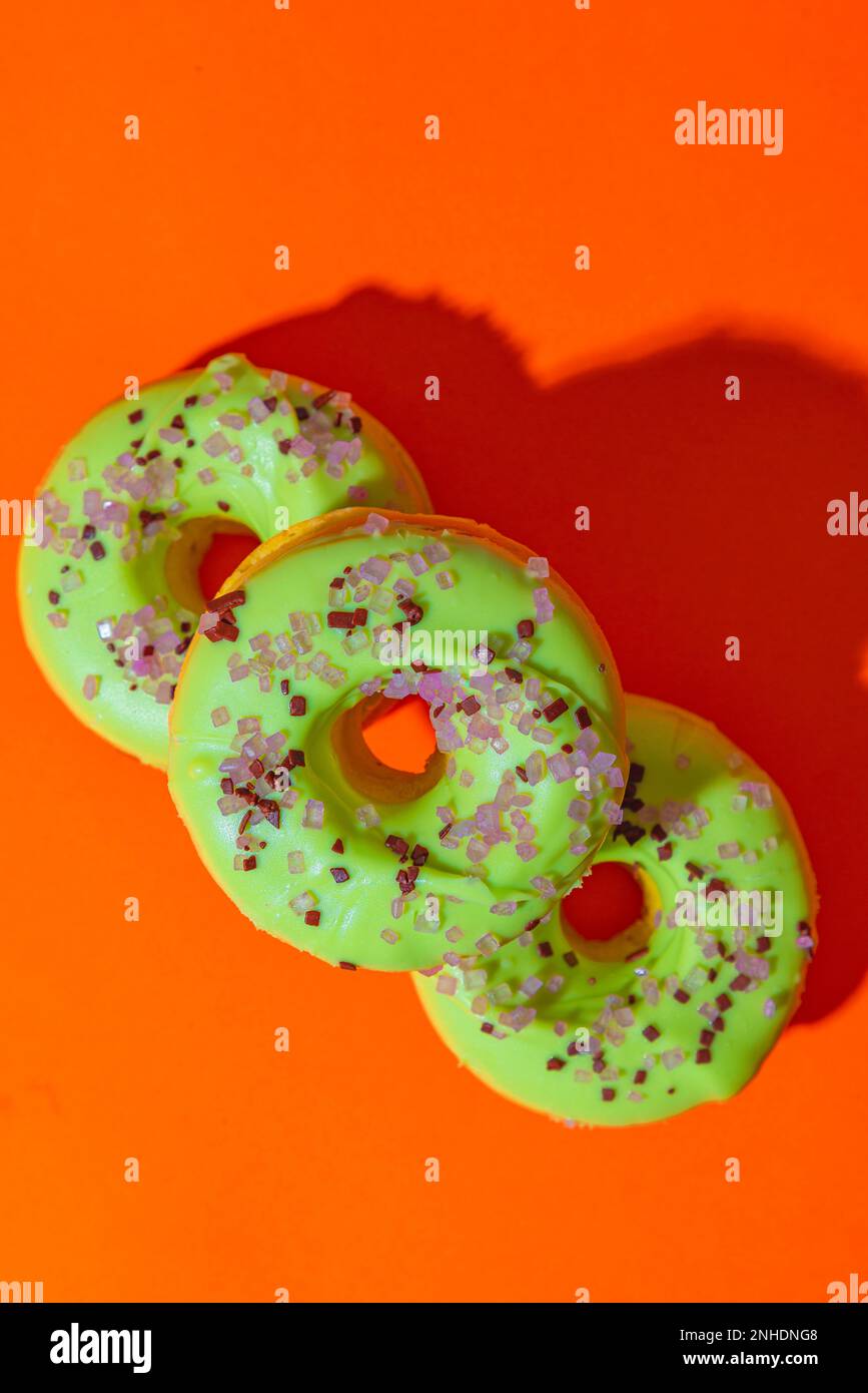 Ciambelle su sfondo arancione con glassa verde, fotografia del cibo Foto Stock
