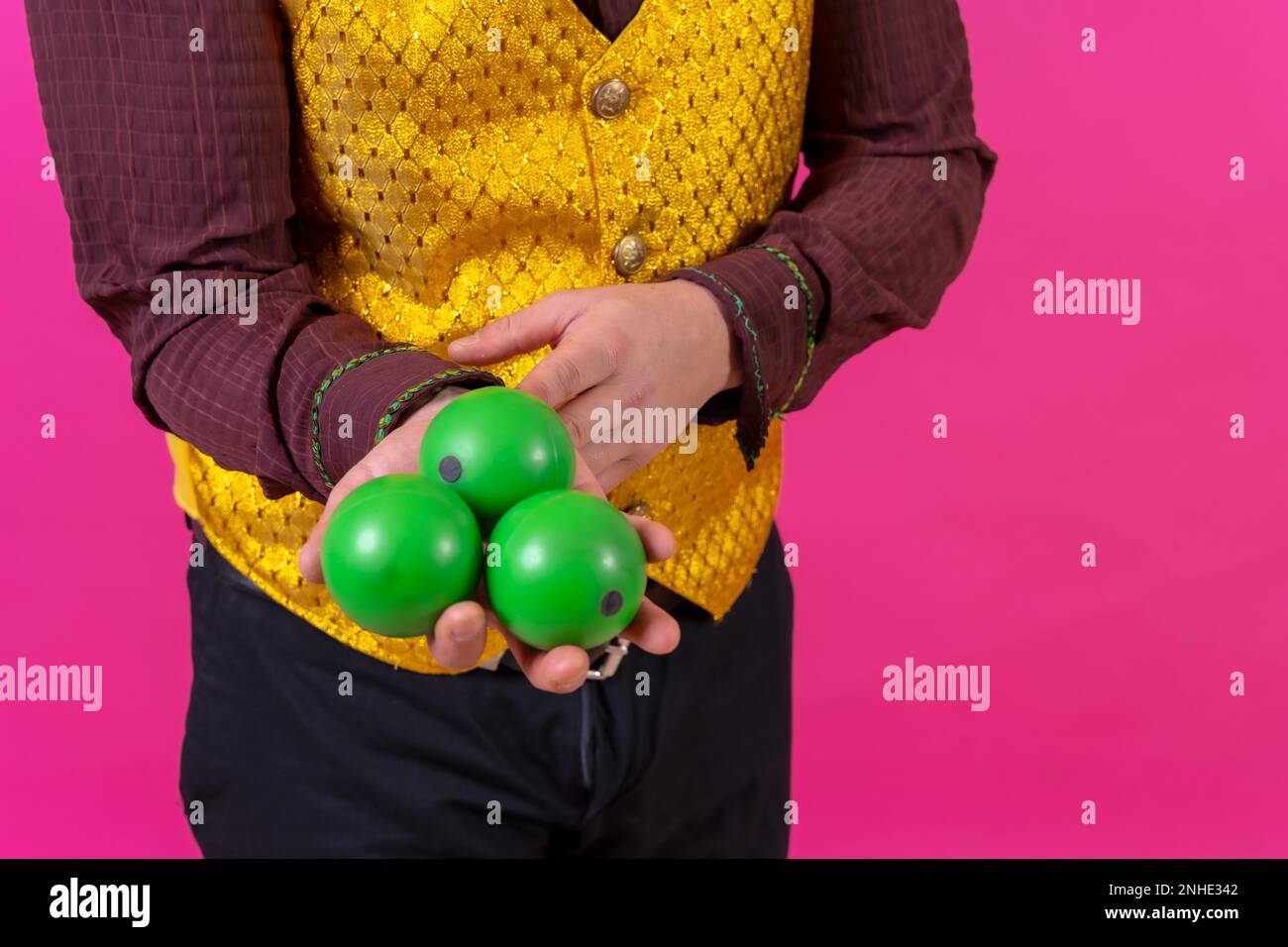 Ritratto di clown con trucco facciale bianco su sfondo rosa, giocolando palle verdi Foto Stock