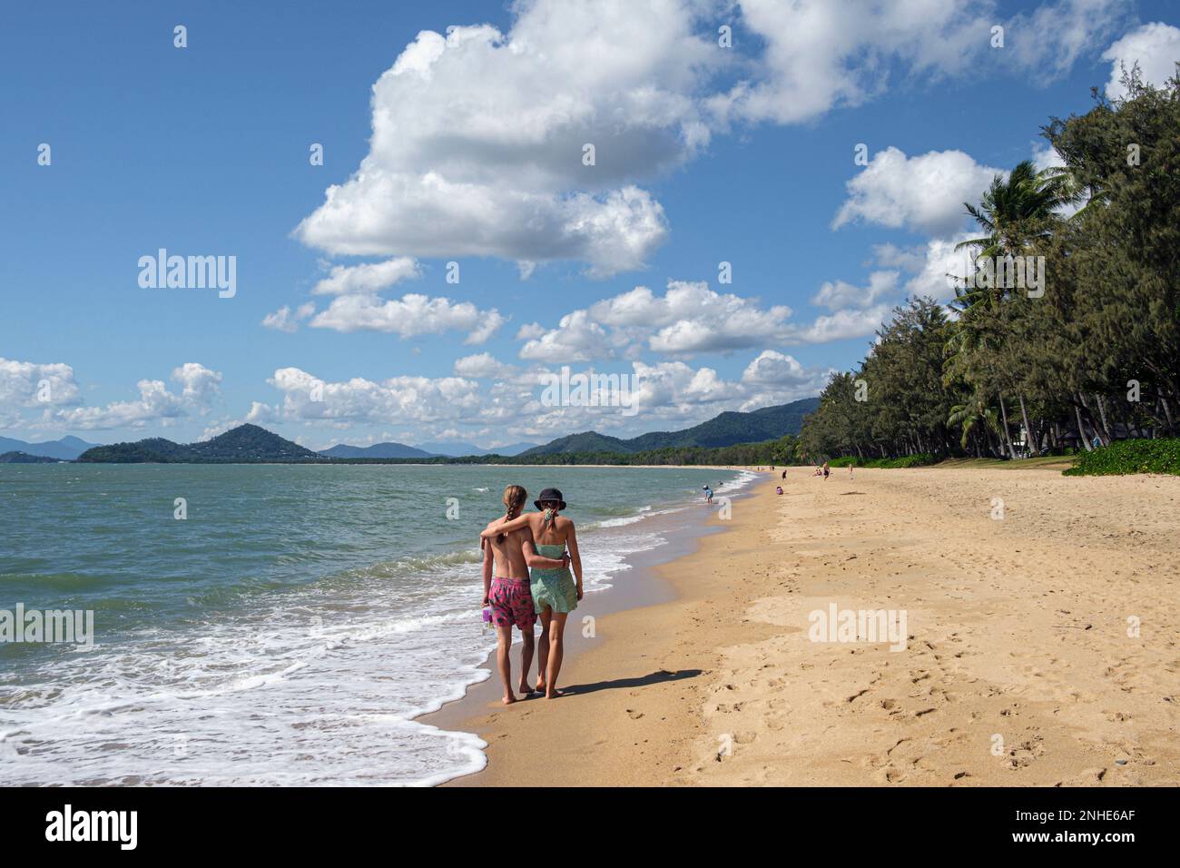 Una giovane coppia cammina di pari passo lungo la spiaggia di Palm Cove, Queensland, Australia Foto Stock