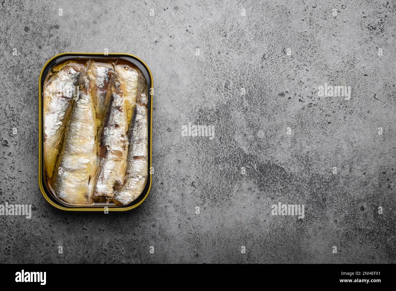 Vista ravvicinata e dall'alto della sardina in scatola su sfondo grigio cemento, spazio per il testo. Pesce in scatola come un cibo conveniente, veloce, sano e. Foto Stock