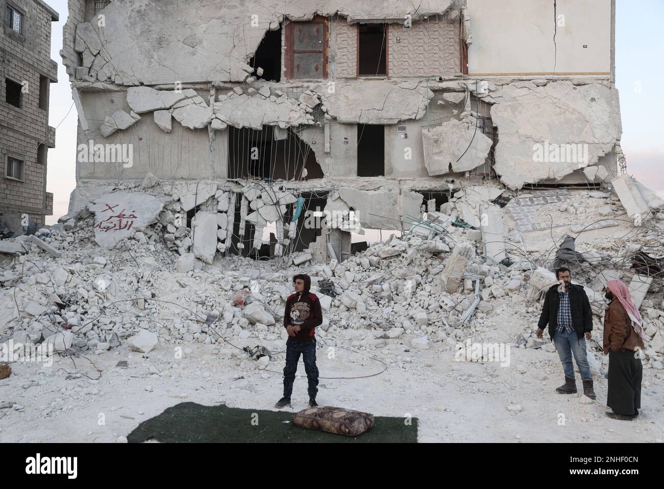 Al Atarib, Siria. 21st Feb, 2023. Muhammad al-Mula, 15 anni, si trova di fronte alla sua casa distrutta a causa del letale terremoto che ha attraversato il confine turco-siriano. Al-Mula è stato salvato dopo essere stato intrappolato per quasi dieci ore sotto i detriti dell'edificio dove aveva vissuto con i suoi cinque membri della famiglia che li hanno persi tutti e ora vive da solo in un rifugio temporaneo nella città di al Atarib. Come risultato della campagna militare contro Aleppo, Muhammed e la sua famiglia sono stati sfollati nella città di al Atarib nel 2016. Credit: ANAS Alkharboutli/dpa/Alamy Live News Foto Stock