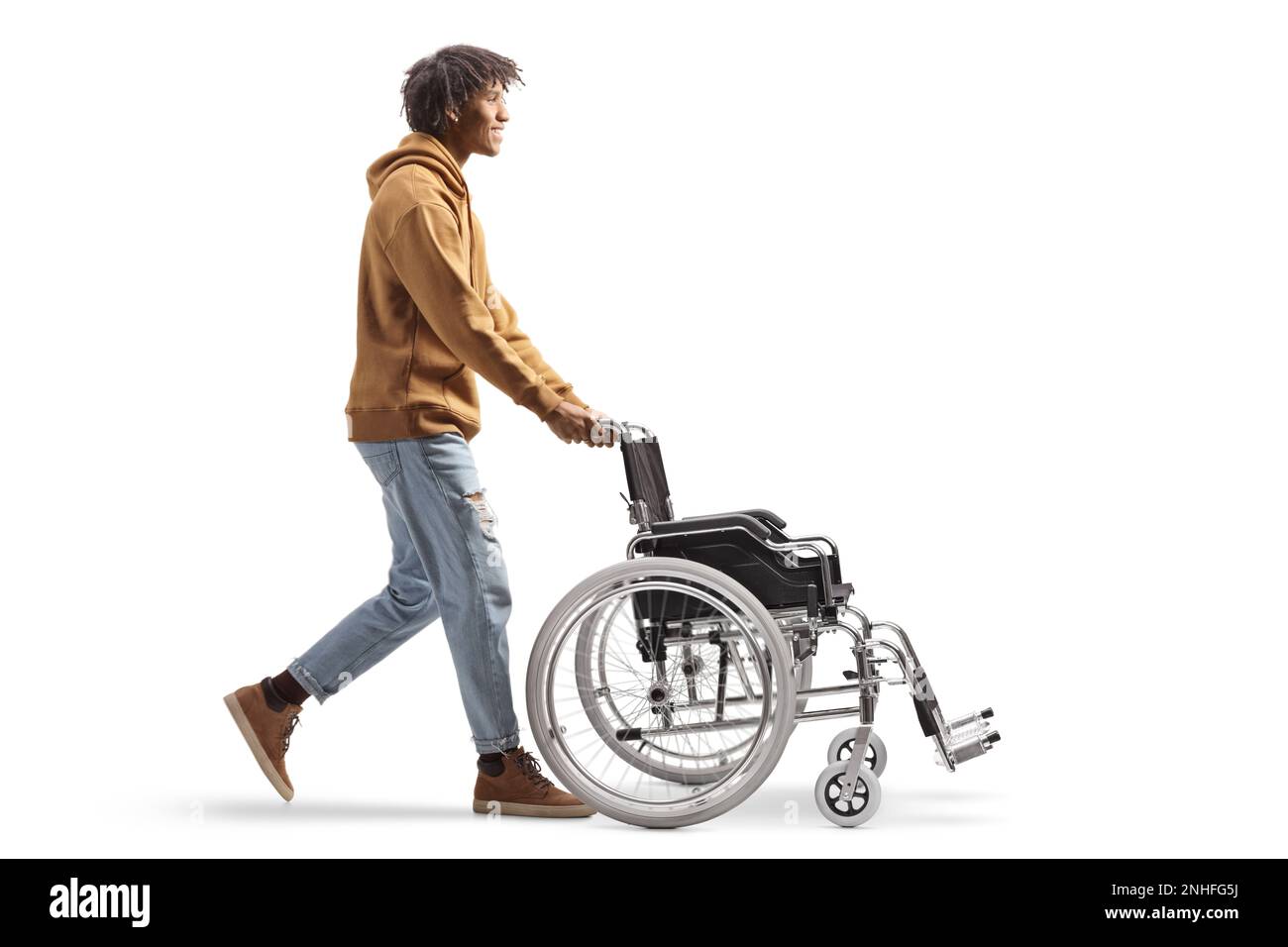 Profilo a tutta lunghezza di un giovane afro-americano che spinge una sedia a rotelle vuota isolata su sfondo bianco Foto Stock