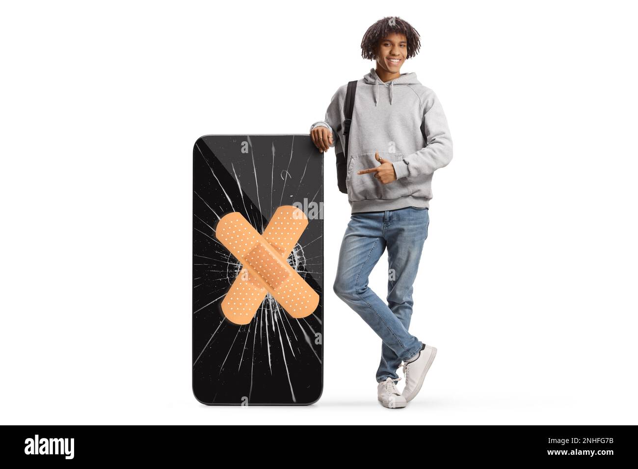 Giovane afro-americano che indica un grande telefono cellulare con schermo incrinato e bendaggio isolato su sfondo bianco Foto Stock