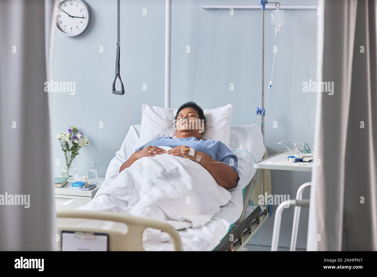 Ritratto di una paziente anziana che dorme sul letto in una stanza d'ospedale con tubi e supporto IV Foto Stock