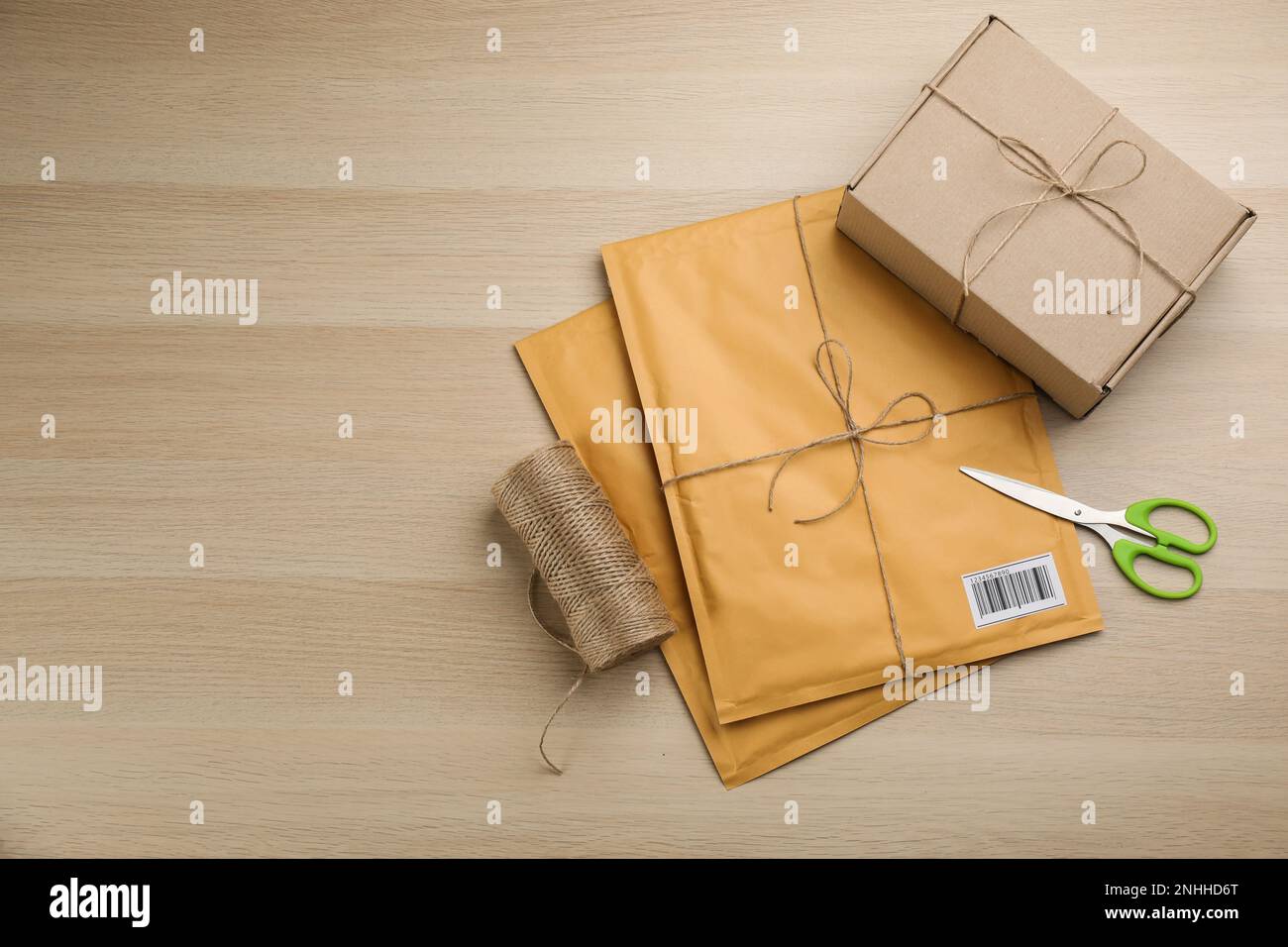 Buste imbottite, scatola, corda e forbici su sfondo di legno, piatto. Spazio per il testo Foto Stock