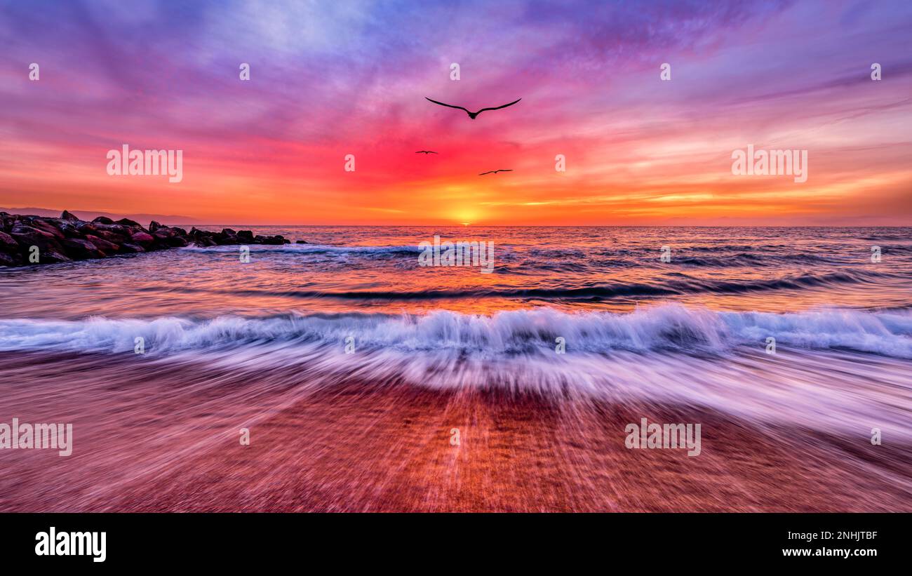 Un gruppo di uccelli sta volando verso il coloratissimo paesaggio del sole raggio tramonto in formato immagine banner Foto Stock