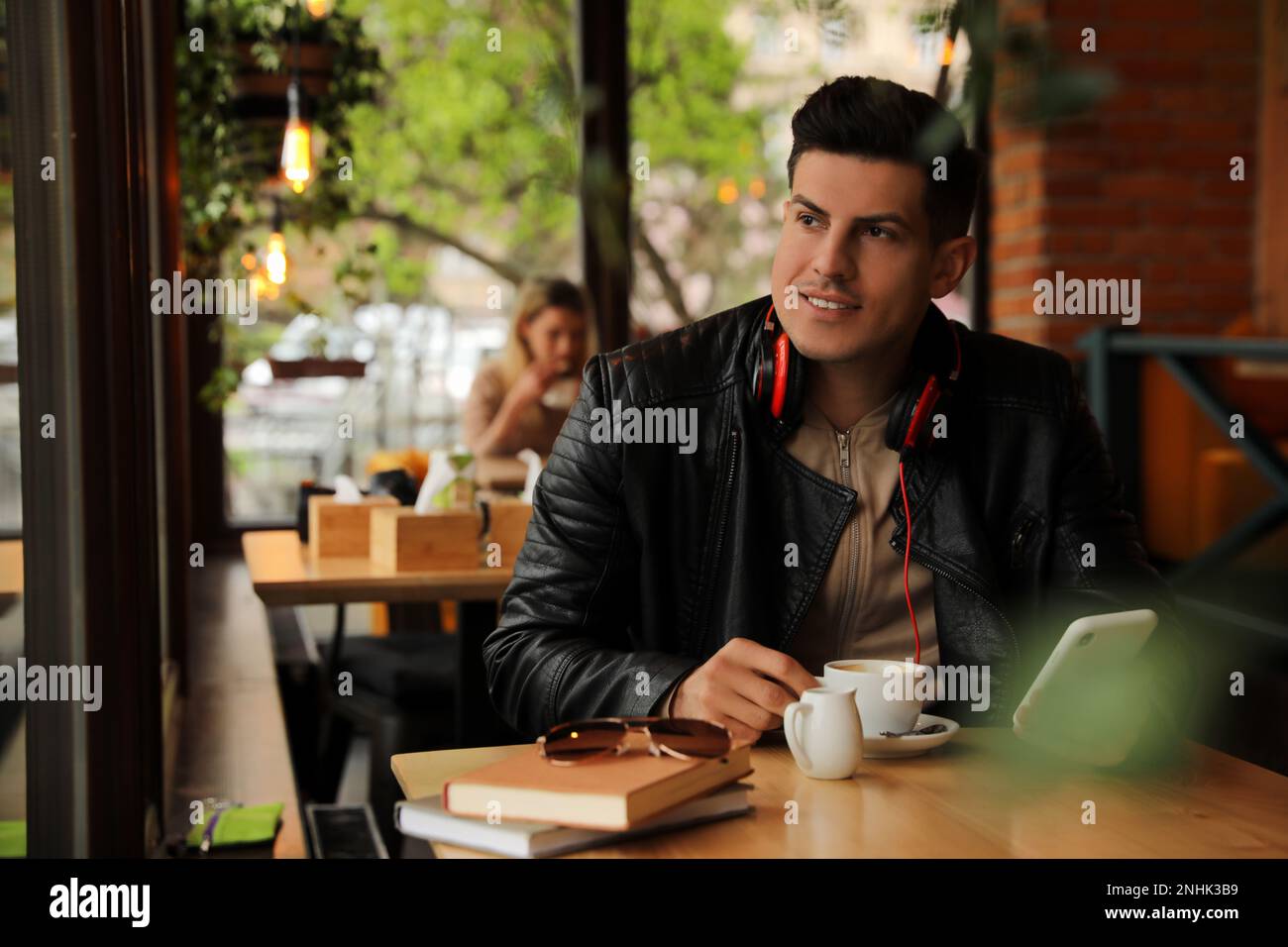 Uomo con cuffie e smartphone al tavolo nel bar Foto Stock