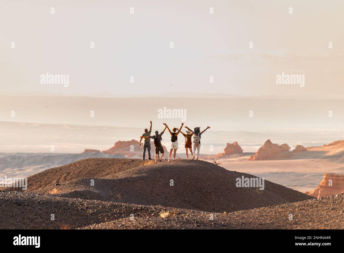 Gruppo di turisti felici si alza a braccia aperte al punto di vista del deserto Foto Stock