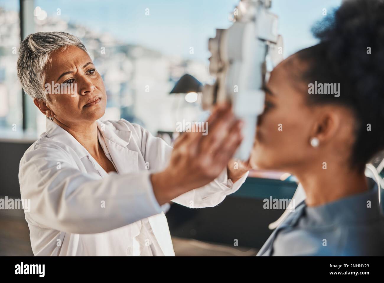 Donna anziana optometristo, paziente esame oculare e obiettivo medico in ospedale, sala di consulenza e ufficio con aiuto. Ottico anziano, esame della vista e. Foto Stock