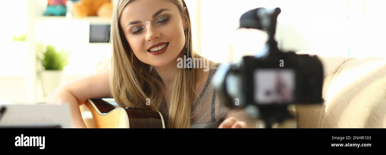 Giovane donna suona la chitarra acustica e registra video clip per i social network Foto Stock