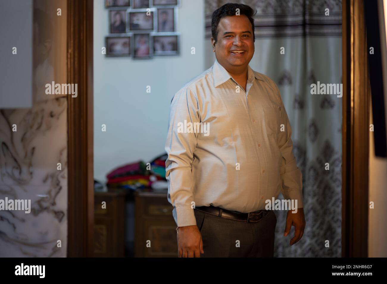 Ritratto di uomo allegro in abiti formali in piedi sulla porta di casa Foto Stock