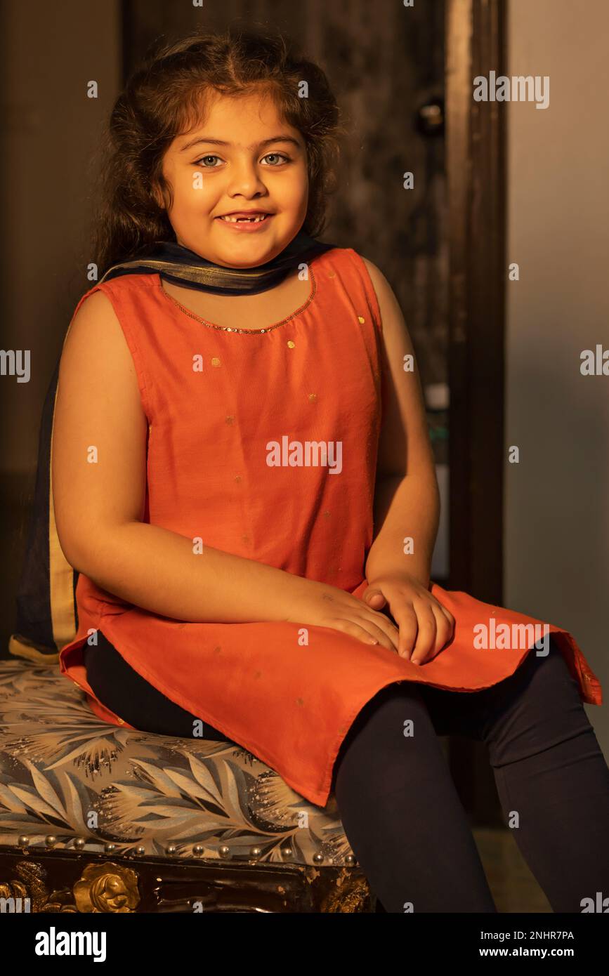 Ritratto di una bambina sorridente seduta sulla sedia a casa Foto Stock