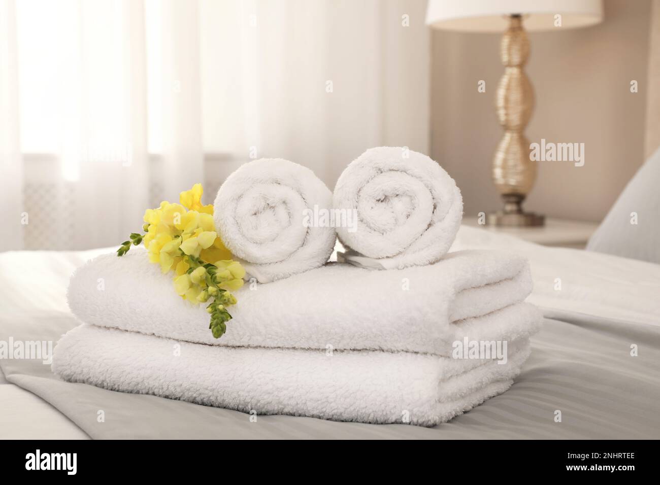 Asciugamani bianchi freschi con fiori sul letto interno Foto stock - Alamy