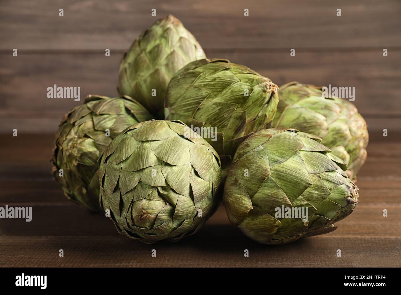 Molti carciofi freschi crudi su tavola di legno Foto Stock