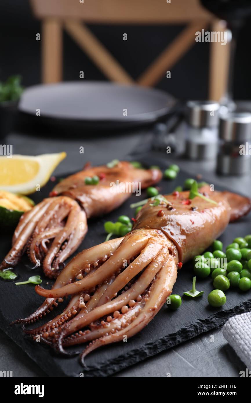 Gustosi calamari alla griglia serviti su un tavolo nero, primo piano Foto Stock