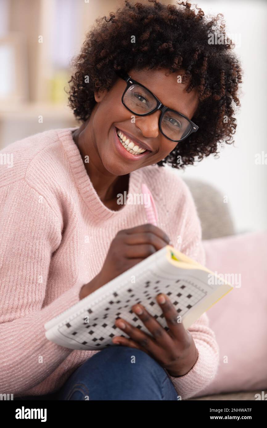 donna che fa parole incrociate in salotto Foto Stock