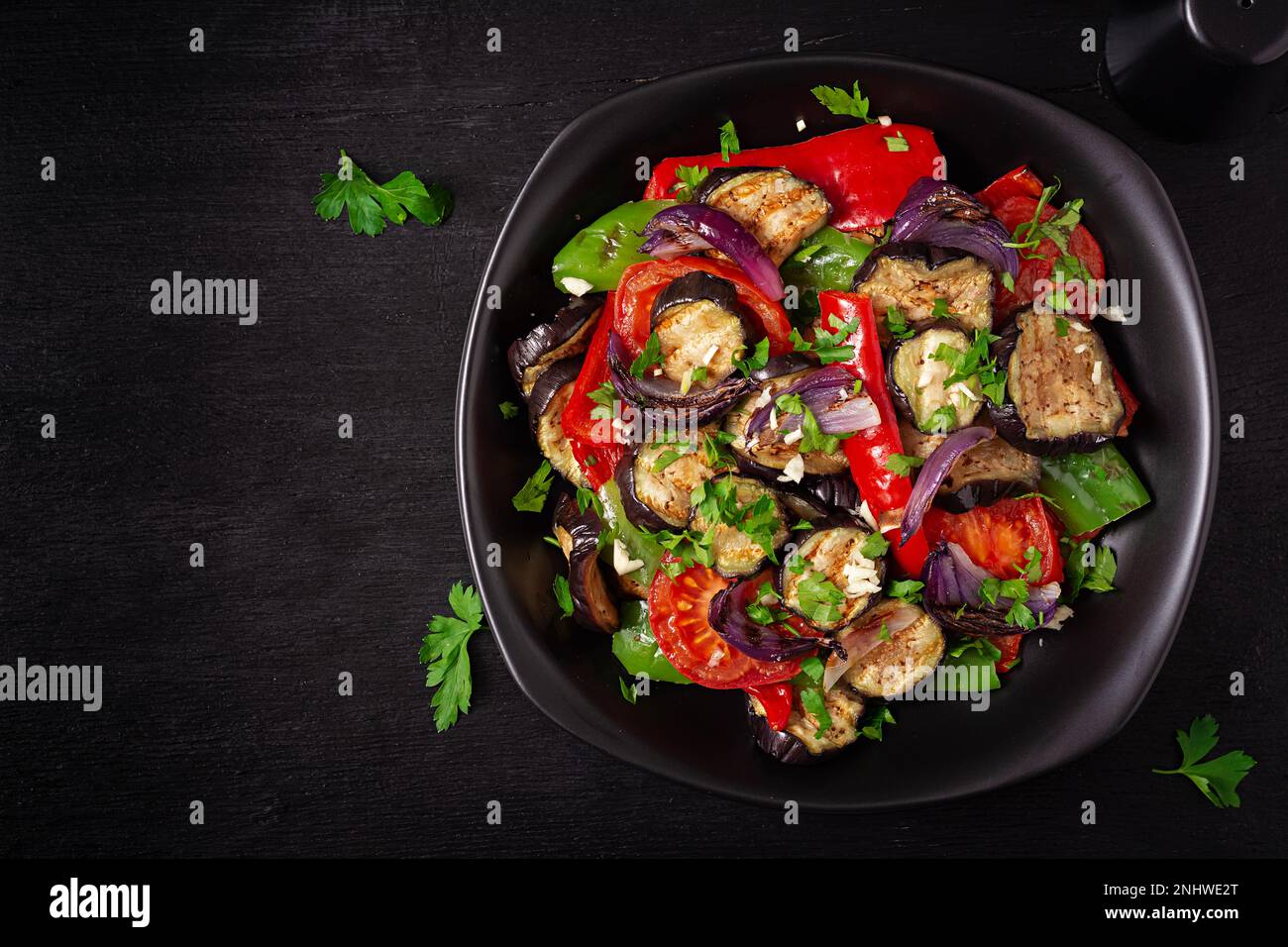 Melanzane alla griglia, peperone, zucchine, cipolla rossa, pomodoro con aglio su un piatto nero. Vista dall'alto, sopra Foto Stock