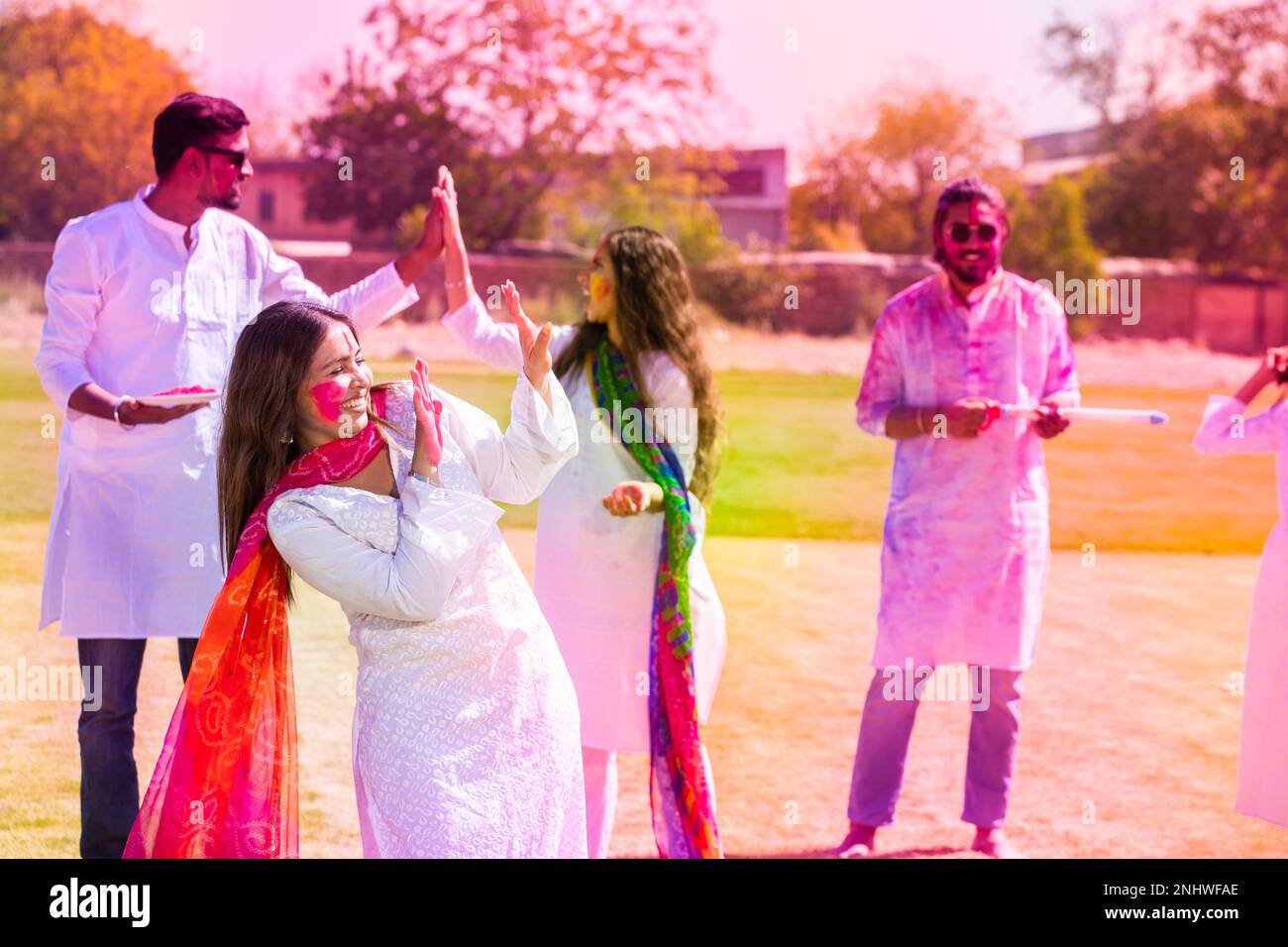 Felici giovani indiani indossando un vestito di kurta bianca che festeggia il festival di holi con polvere colorata o gulal al parco all'aperto. Foto Stock