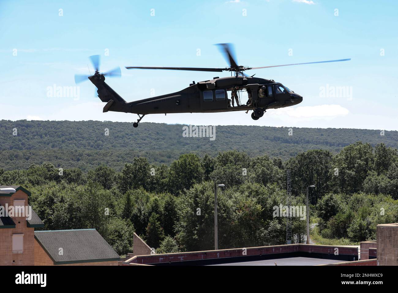 I soldati con sede centrale e sede centrale, 1st battaglione, 110th reggimento di fanteria, 28th divisione di fanteria, osservano la zona di atterraggio in un falco nero UH-60 della Brigata dell'aviazione di combattimento Expeditionary 28th durante una missione di addestramento di rappelling a Fort Indiantown Gap, Pa., il 3 agosto 2022. I soldati si sono respinti dal Black Hawk come l'evento finale dell'allenamento, che ha incluso la marcia con i fuck e i bersagli coinvolgenti. Foto Stock