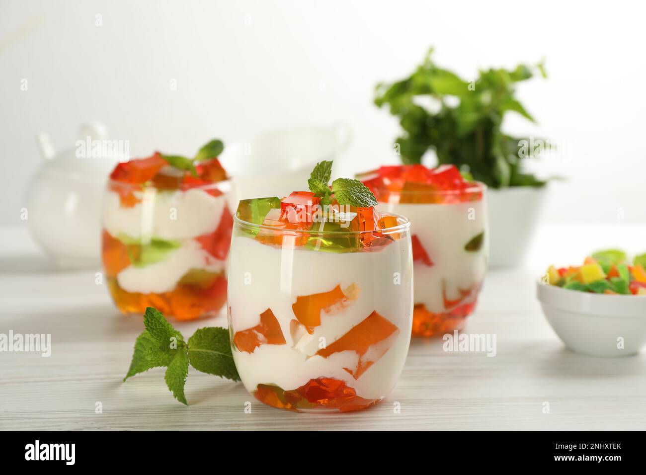 Delizioso dessert di gelatina di vetro spezzato su un tavolo di legno bianco Foto Stock